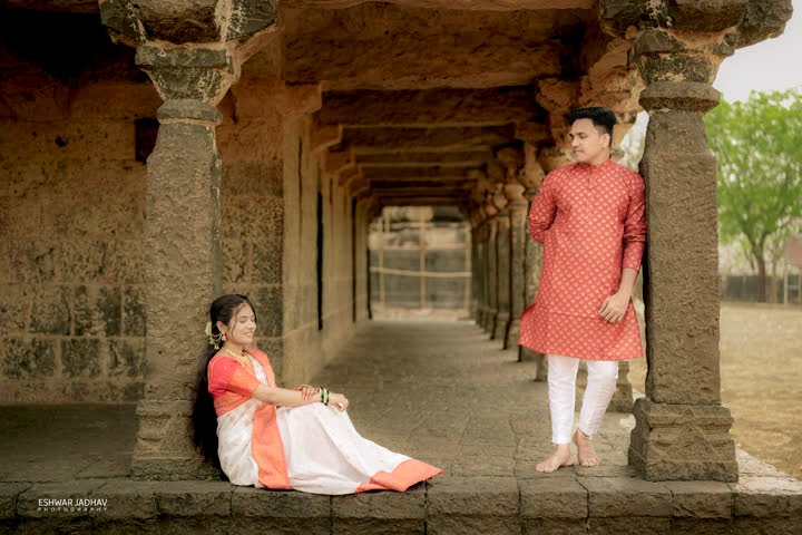 Bride seated on the colonnade floor while the groom leans on a pillar